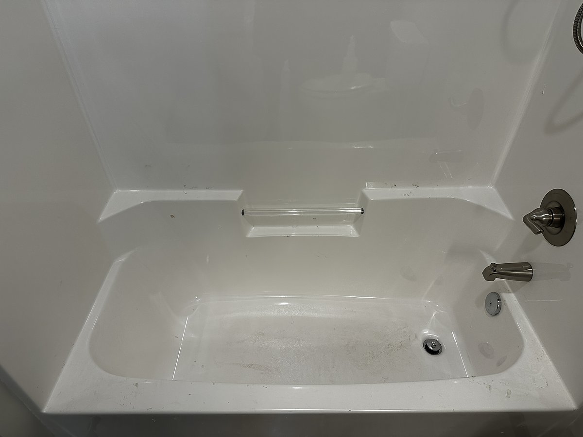 Shower before a Mopp deep clean in River Falls, WI, with hard-water buildup and soap scum on the tile and fixtures