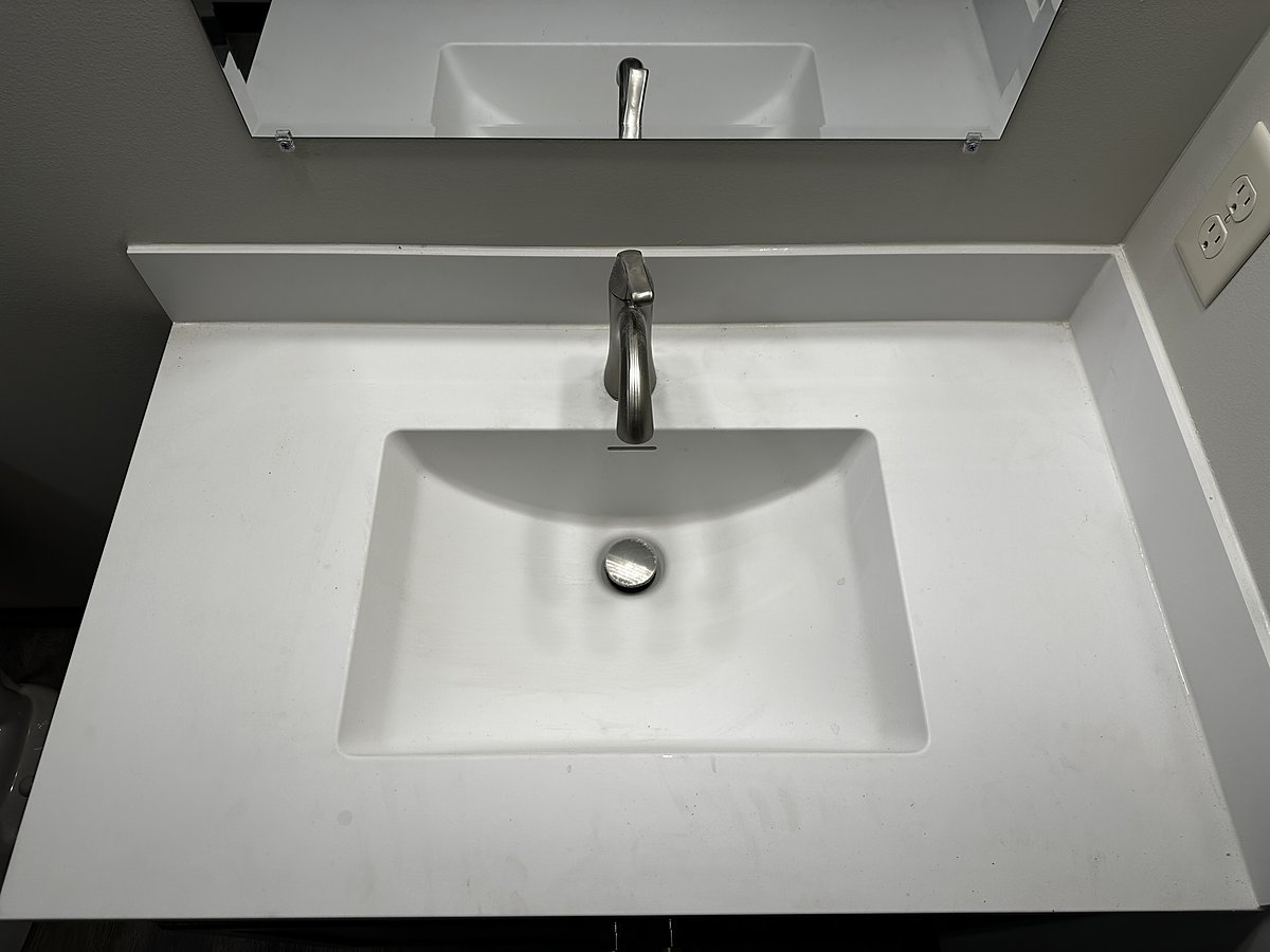 Bathroom sink and fixtures before a Mopp deep clean, dulled by water spots and mineral buildup